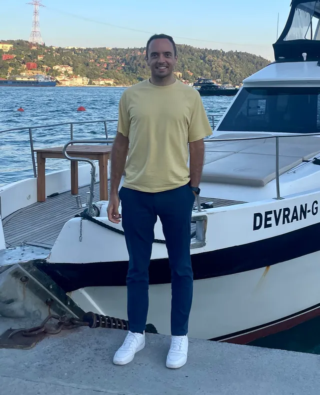 Gabriele Polenta, relaxed, standing on a dock in front of a boat